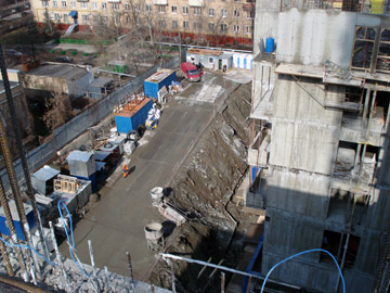 Вид со строящихся секций жилого комплекса на временную строительную площадку, размещенную на грунтовой берме на месте стилобата подземной части комплекса.